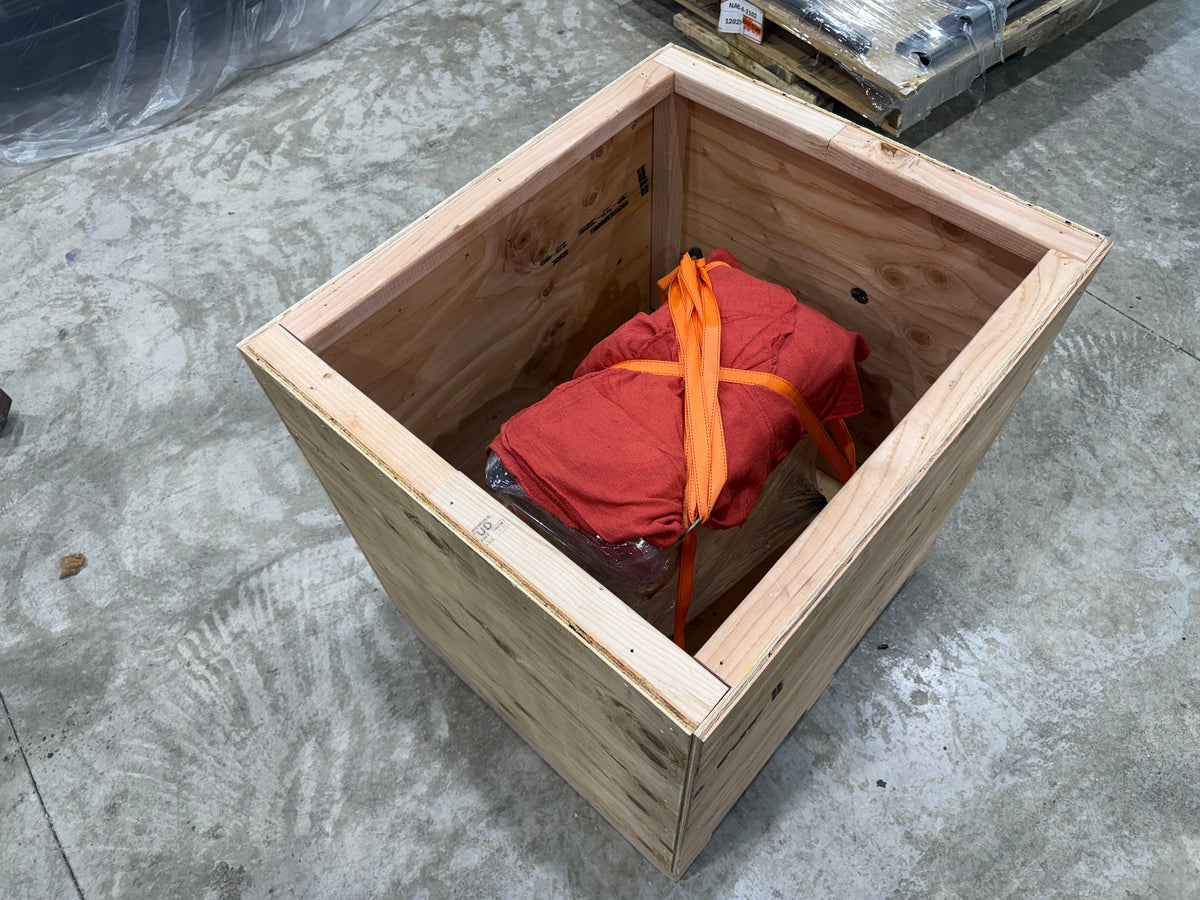 Wrapped engine strapped down inside an open wooden shipping crate