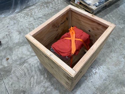 Wrapped engine strapped down inside an open wooden shipping crate