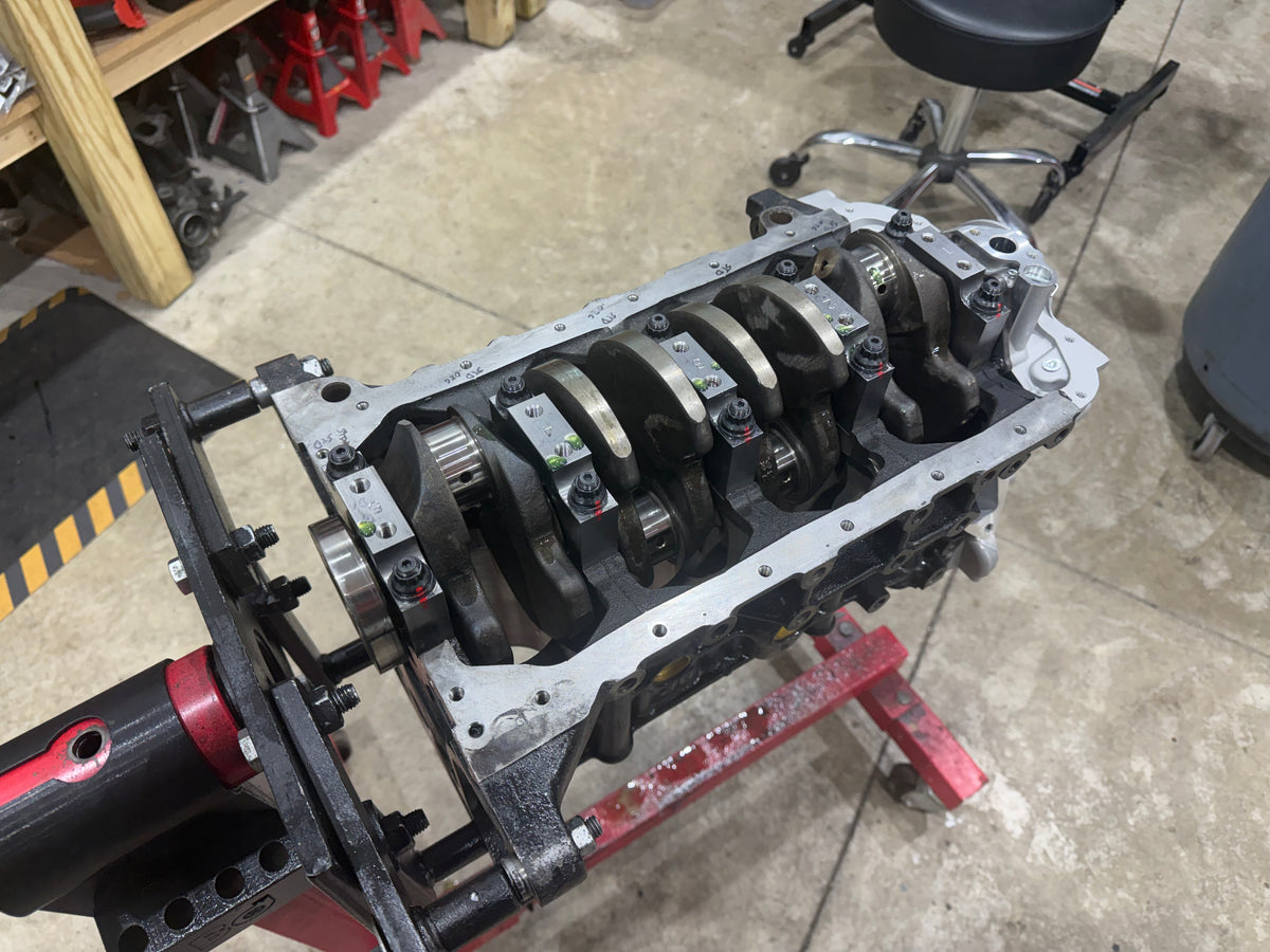 Engine block upside down on a stand with the crankshaft and main caps installed
