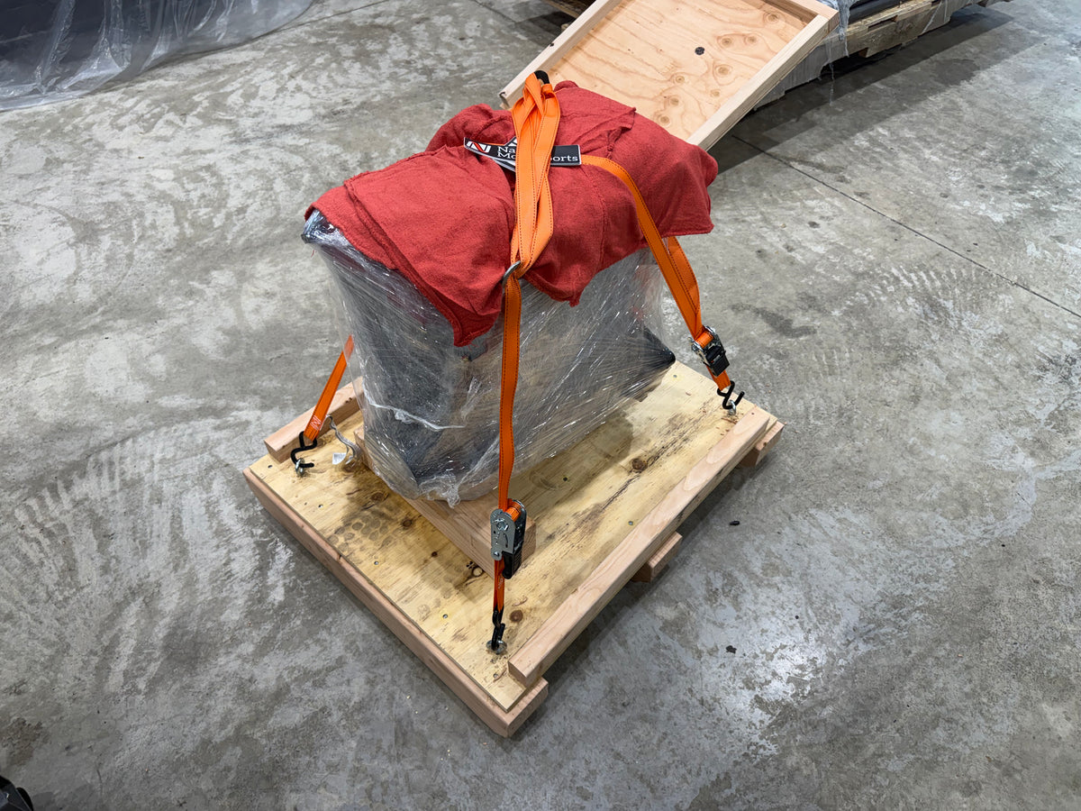 Engine wrapped in plastic and shop towels, strapped to a wooden crate base for shipping